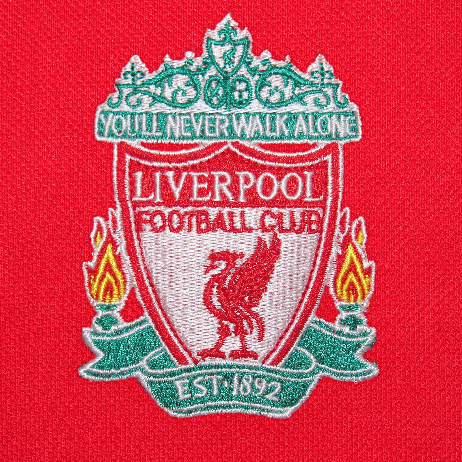 Liverpool adults polo shirt in red with LFC badge and Liverpool FC text to chest.