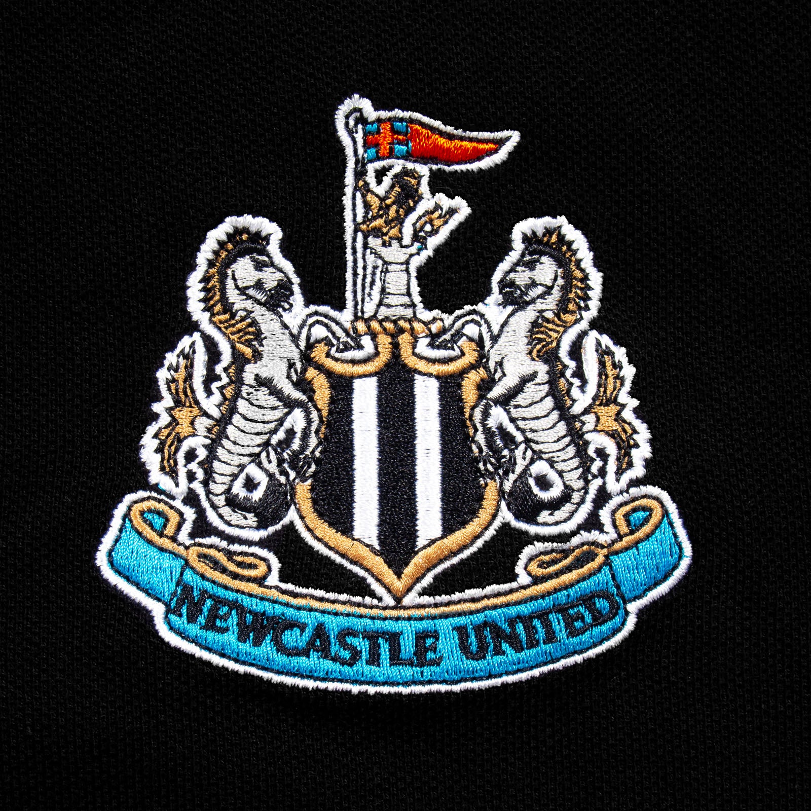 Newcastle Utd adults polo shirt in black with NUFC badge and text to chest.