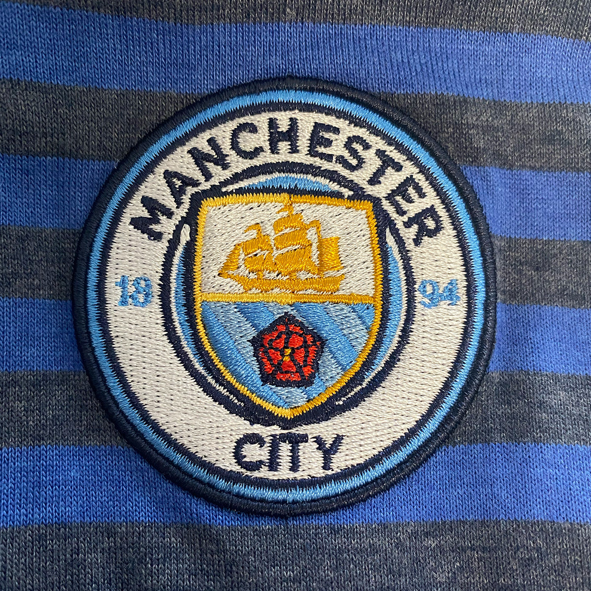 Man City adults striped polo shirt in blue with club crest to chest.