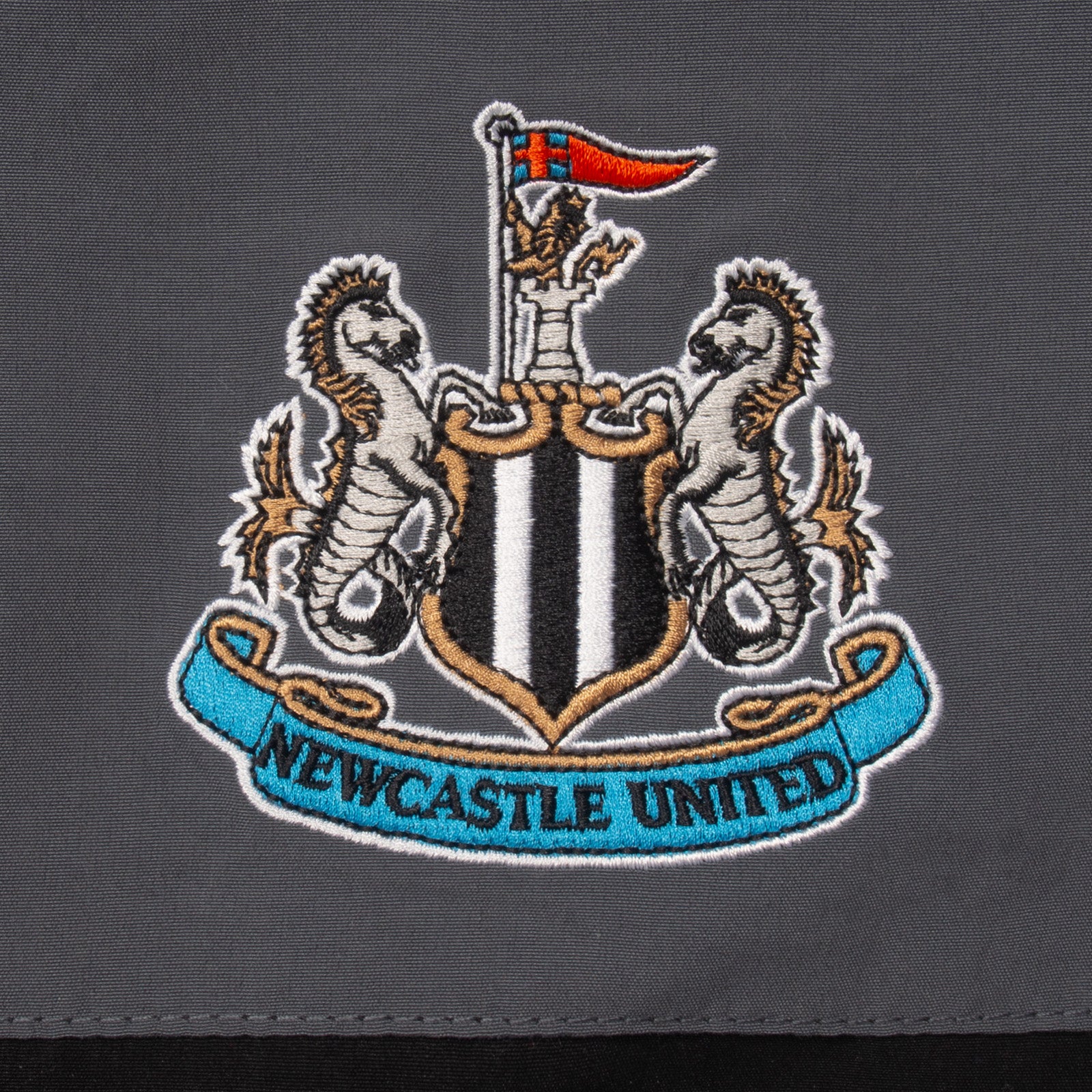 Newcastle Utd kids tracksuit in black with club crest to chest and left thigh