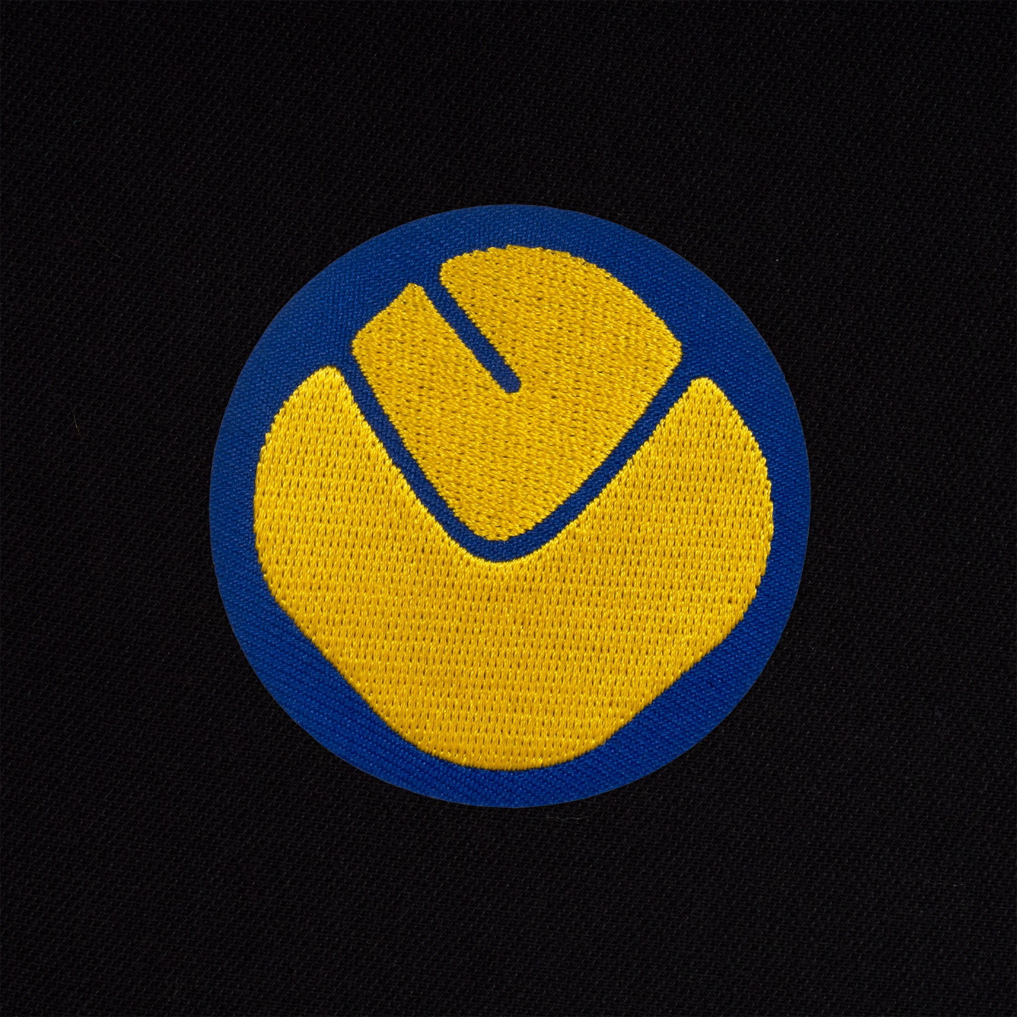Leeds retro polo shirt in black with a smiley embroidered crest applique patch to chest