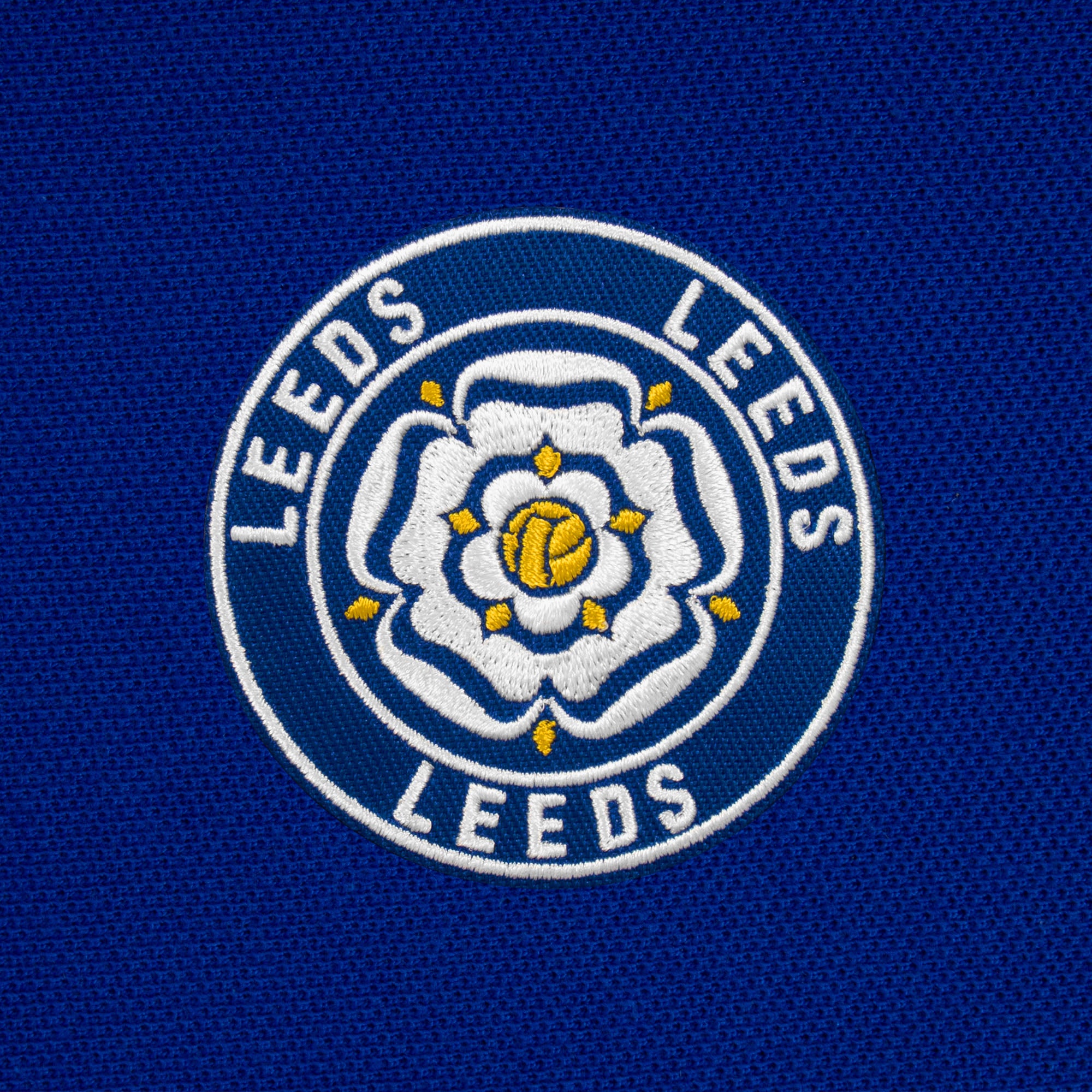 Leeds retro polo shirt in royal with a rose embroidered crest applique patch to chest