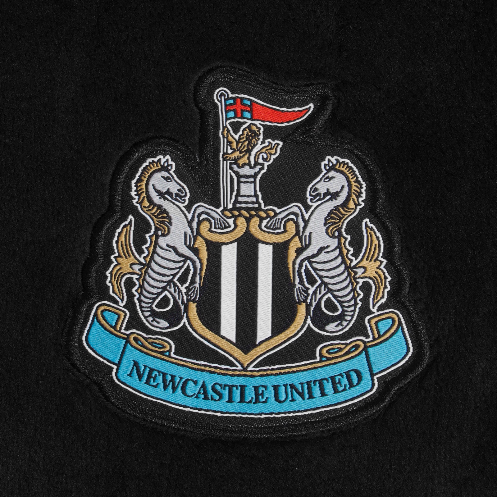 Newcastle United kids all-in-one hooded fleece with all over print team crest.