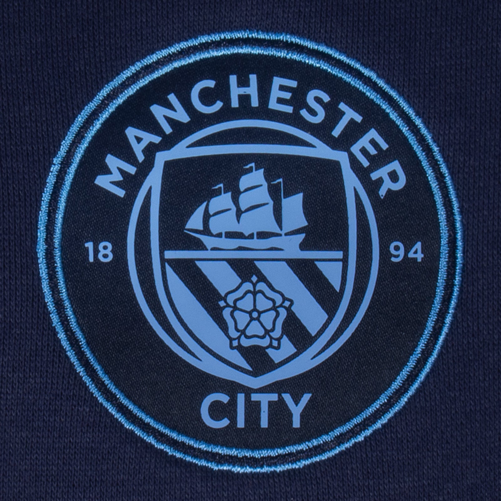 Manchester City adults taped sweatshirt in navy blue with club crest to chest and text to sleeves.